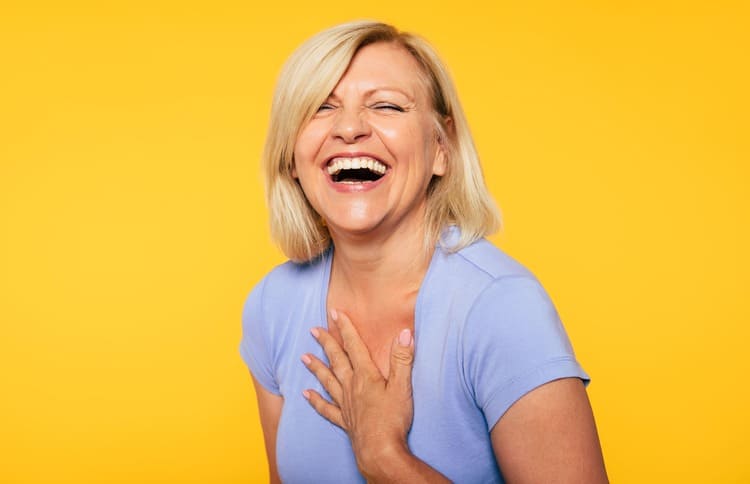 Frau herzhaft lachend, gelber Hintergrund