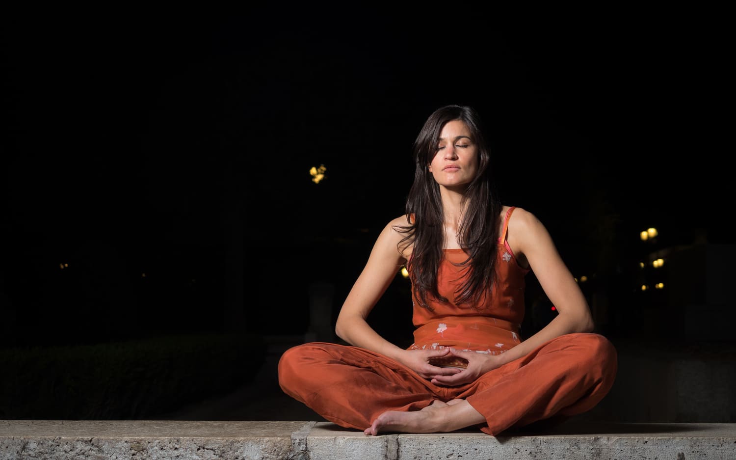 Frau sitzt in absoluter Ruhe und meditiert, schwarzer Bildhintergrund