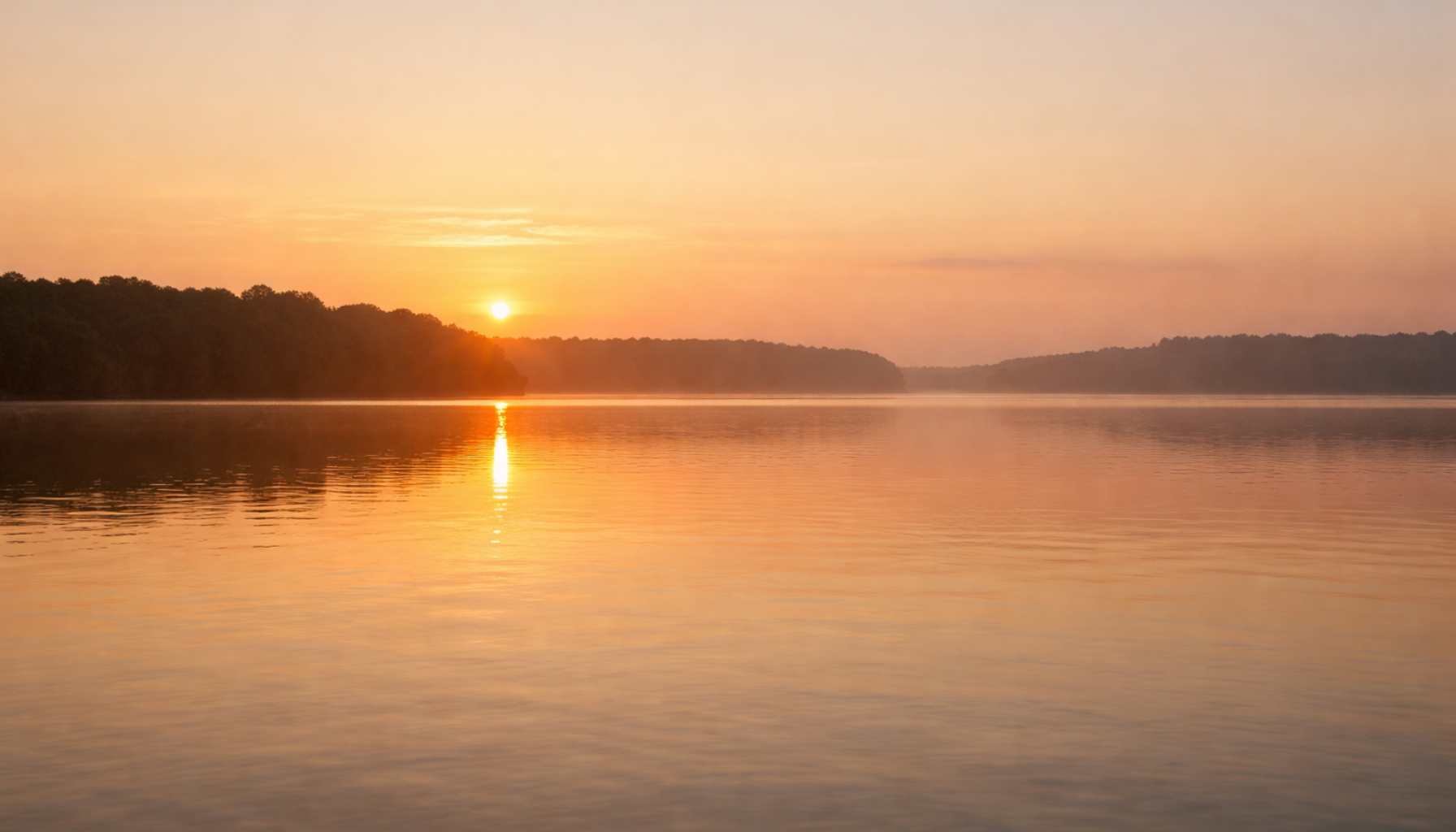 ORÉVYN Ruhige Wasserfläche im warmen Morgenlicht mit weiter Horizontlinie